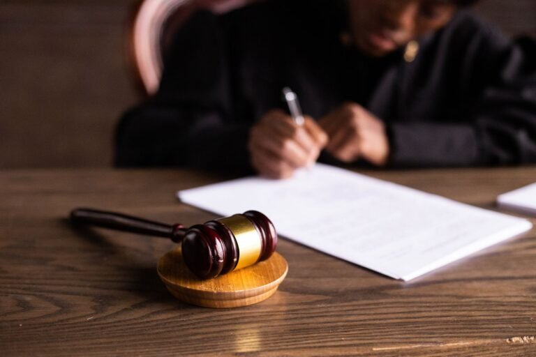Persona con vestimenta judicial revisa y firma documentos, fotografía de archivo ilustrativa sobre resoluciones administrativas.